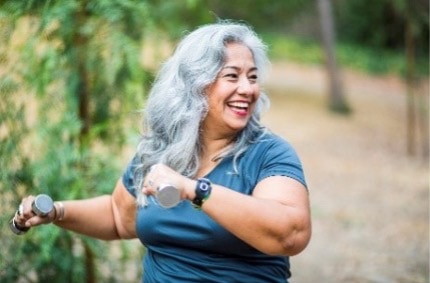 woman walking outside with dumbells in her hands